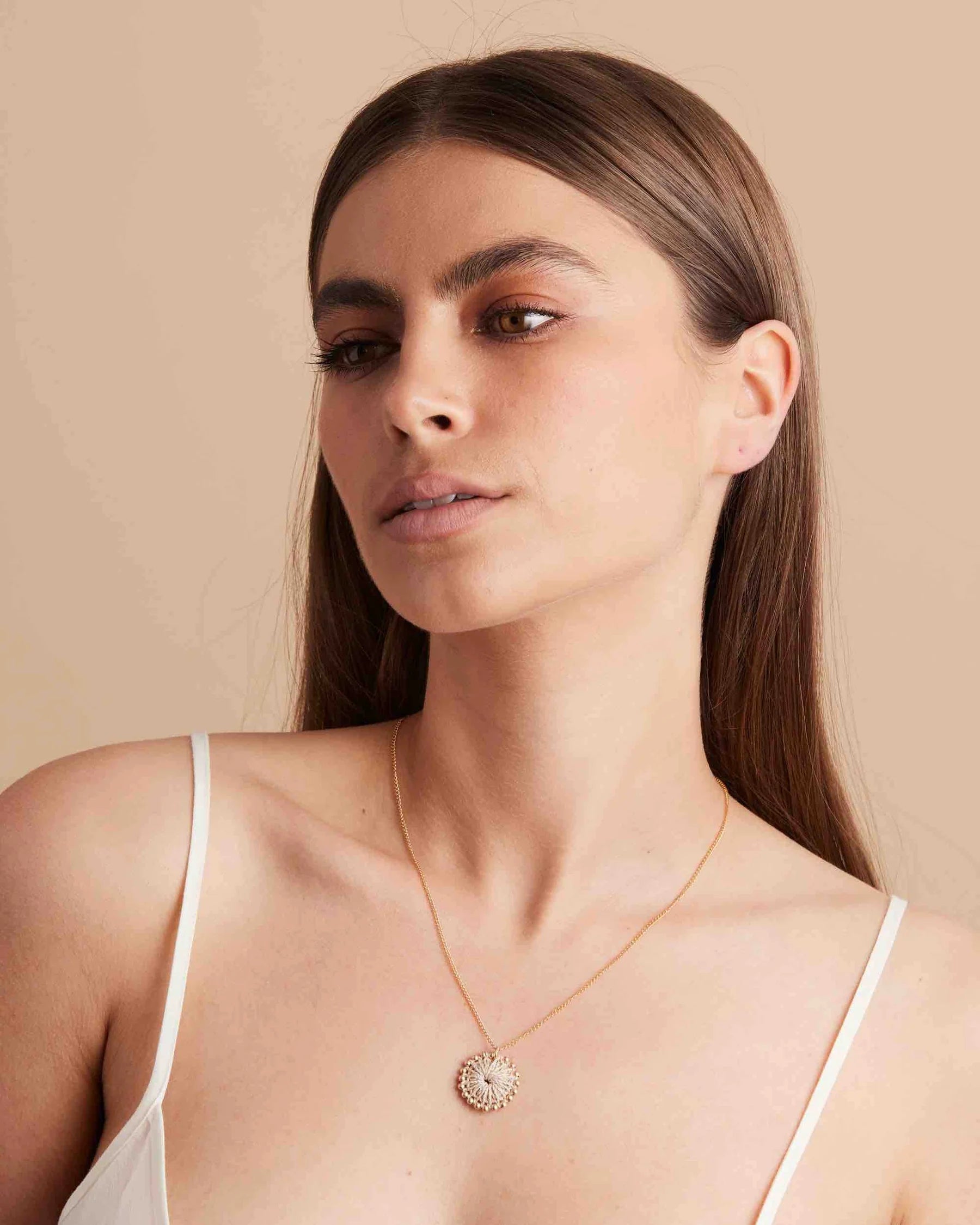 Gold-Necklace-With-Woven-Gold-Beaded-Pendant-Bilum-and-Bilas-on-Model-glancing.webp